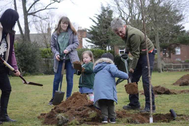 Volunteers from the Ipswich Tree Warden Network digging holes for tree planting in a suburban area.