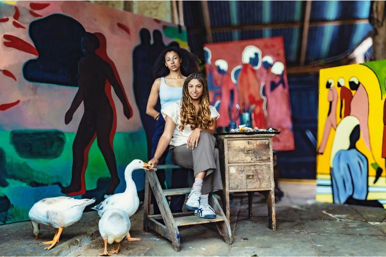Two women artists pictured with their paintings