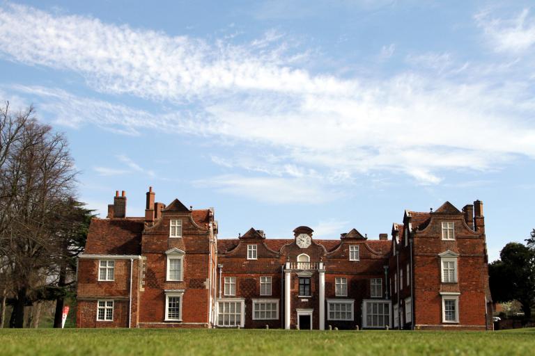 A Tudor building set in a park, seen from a distance