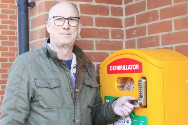 Cllr Ross at Dundee House next to a defibrillator