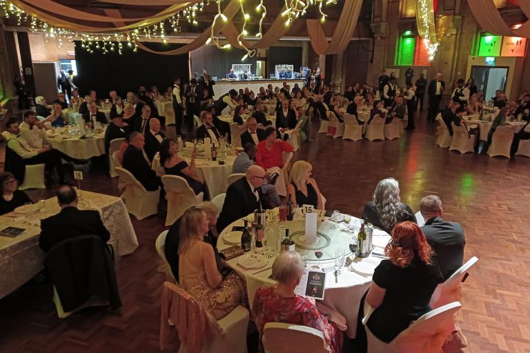 Guests seated at tables in ballroom decorated for a formal event