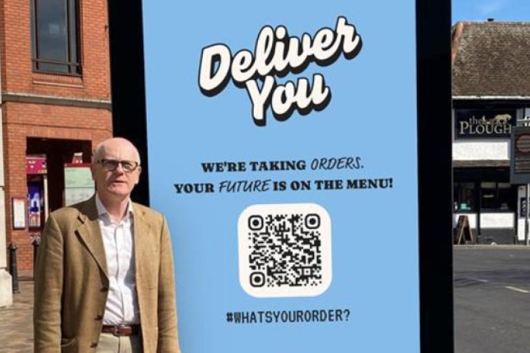 Councillor Neil MacDonald standing next to one of the digital screens in Ipswich town centre.