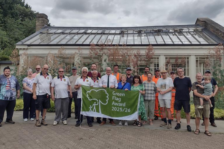 Group of people display Green Flag awarded to Holywells Park in Ipswich