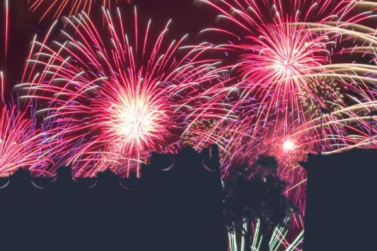 A night sky fill of fireworks over silhouetted buildings