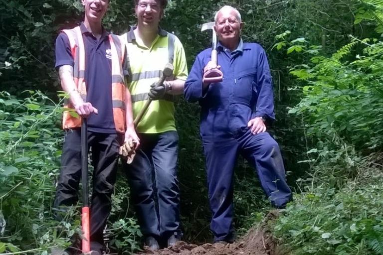 Three volunteers stand holding tools at the top of a flight of stairs they have repaired at the dales local nature reserve