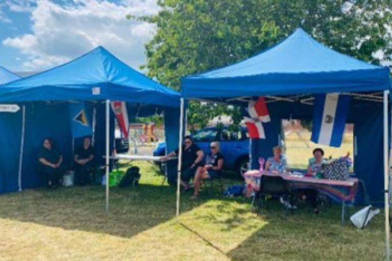 volunteers under gazebos at an event in Murray Park