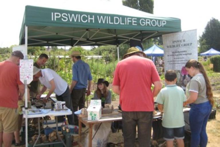 a group of volunteers and members of the public build wildlife homes under a gazebo