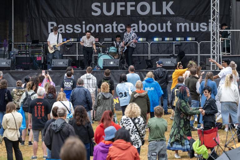 A crowd of people in front of a music stage in Christchurch Park, Ipswich