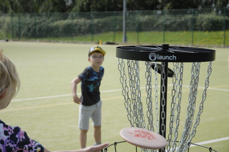 A boy in a sports field playing frisbee golf