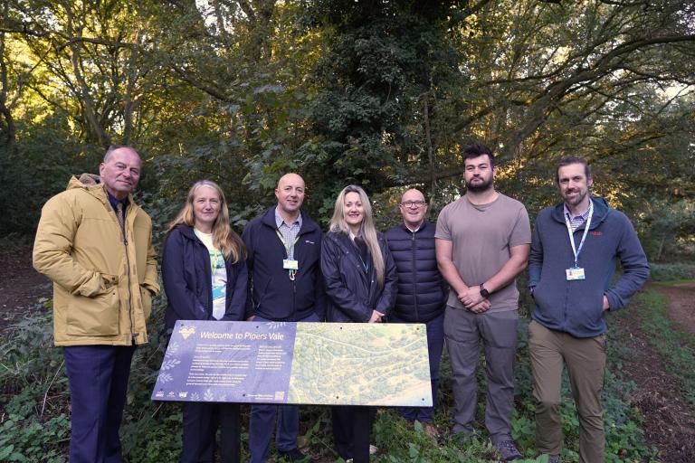 A group of seven people standing around a sign in a country park