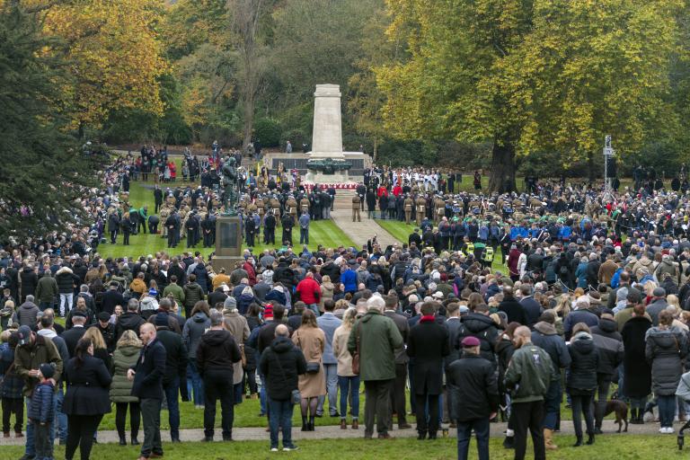A crowd of people surrounding a war memorial in a park in Ipswich