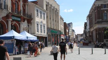 People walking by market stalls and town centre shops