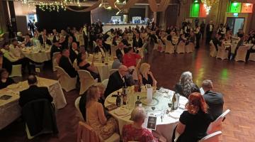 Guests seated at tables in ballroom decorated for a formal event