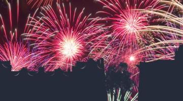 A night sky fill of fireworks over silhouetted buildings