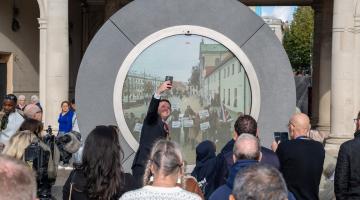 A crowd of people in front of a circular Portal sculpture in Ipswich