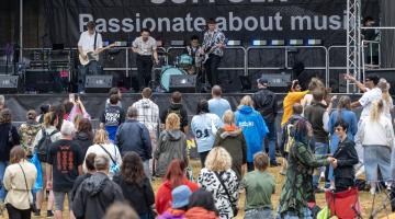 A crowd of people in front of a music stage in Christchurch Park, Ipswich