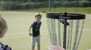 A boy in a sports field playing frisbee golf