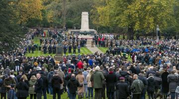 A crowd of people surrounding a war memorial in a park in Ipswich